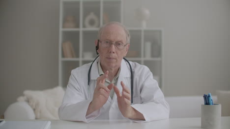 portrait-of-professor-of-medicine-conducting-webinar-from-his-office-in-clinic-aged-man-is-looking-at-camera-and-speaking